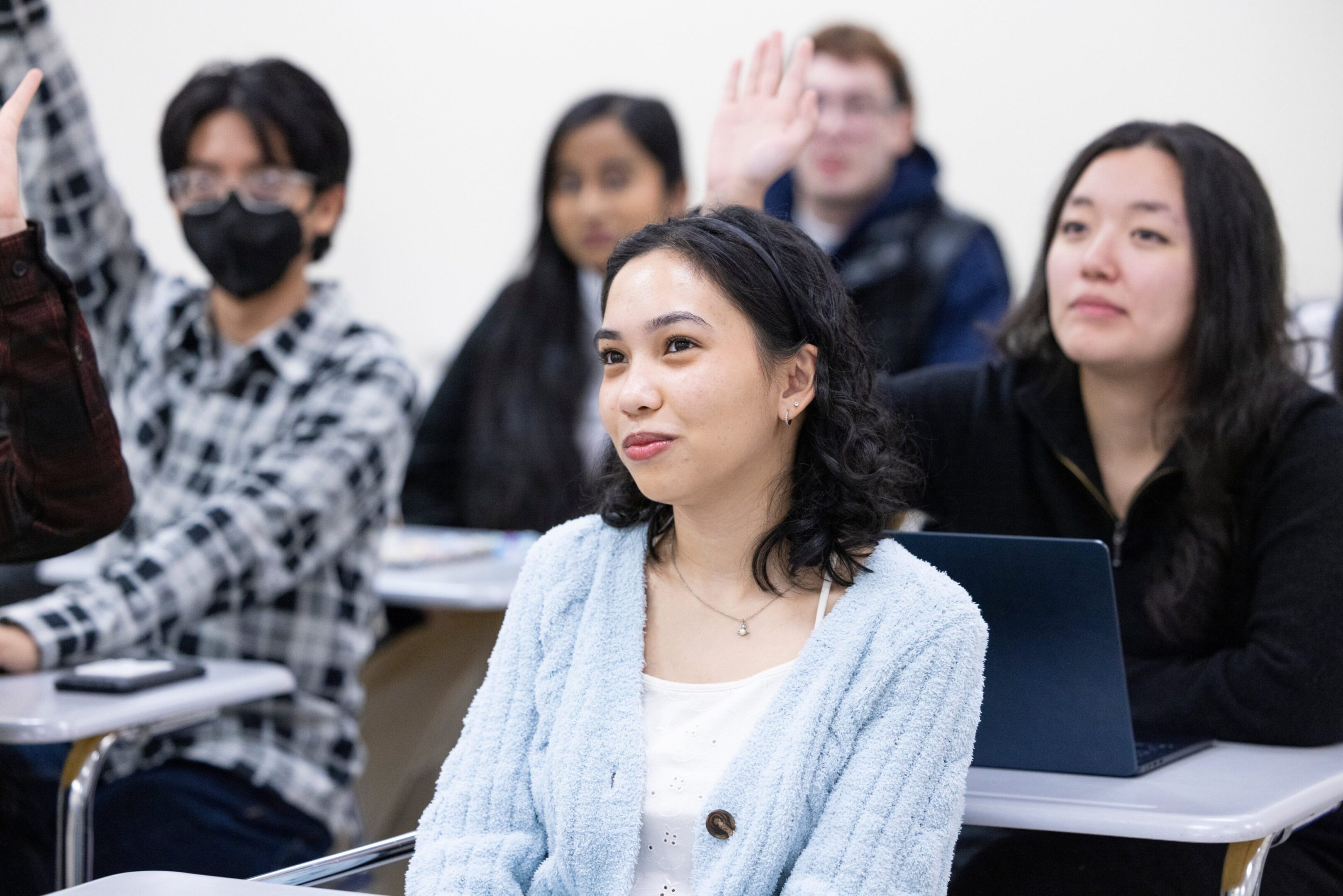 A woman raising her hand in a classroom setting.