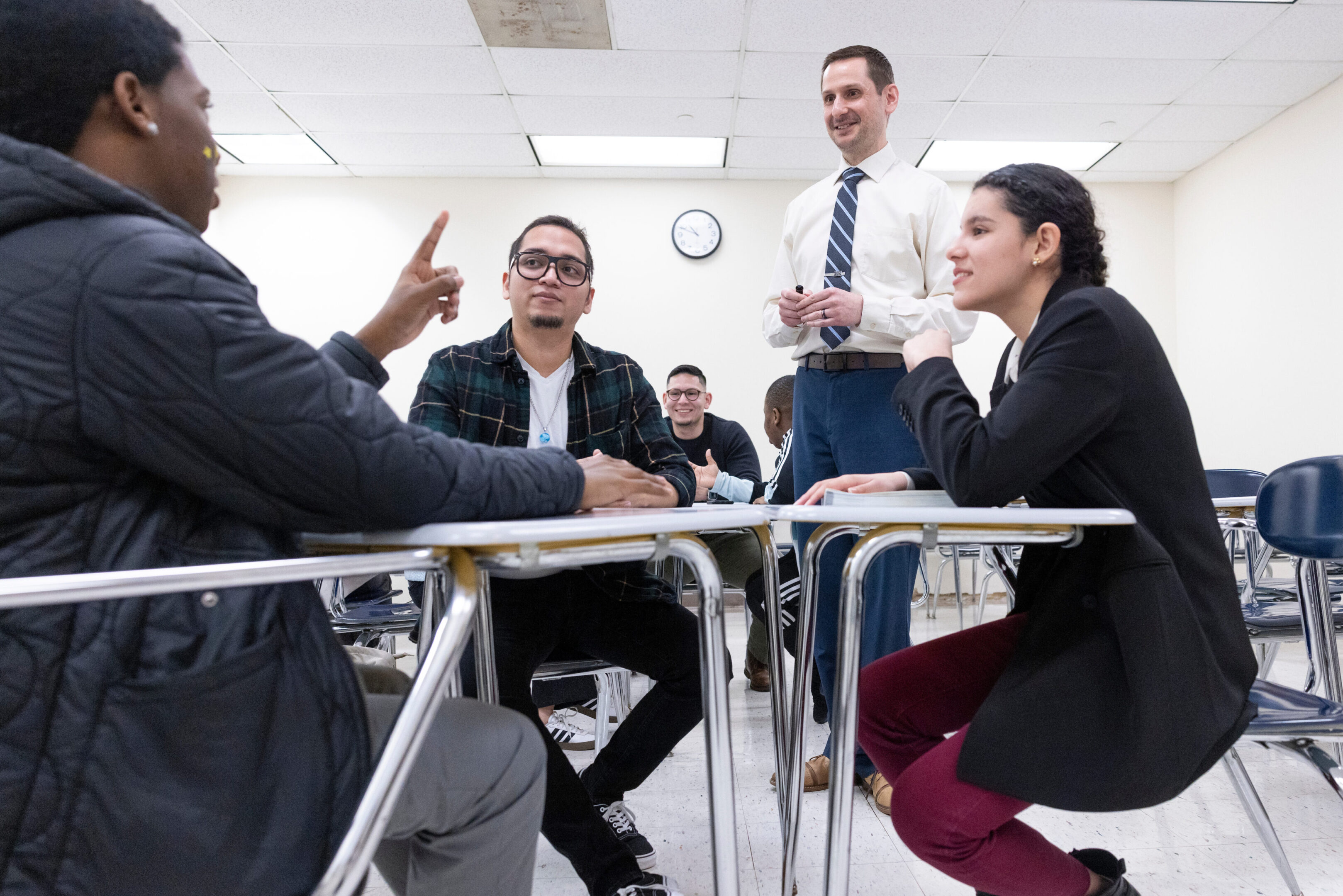 People engaged in a lively discussion around a table in a classroom.