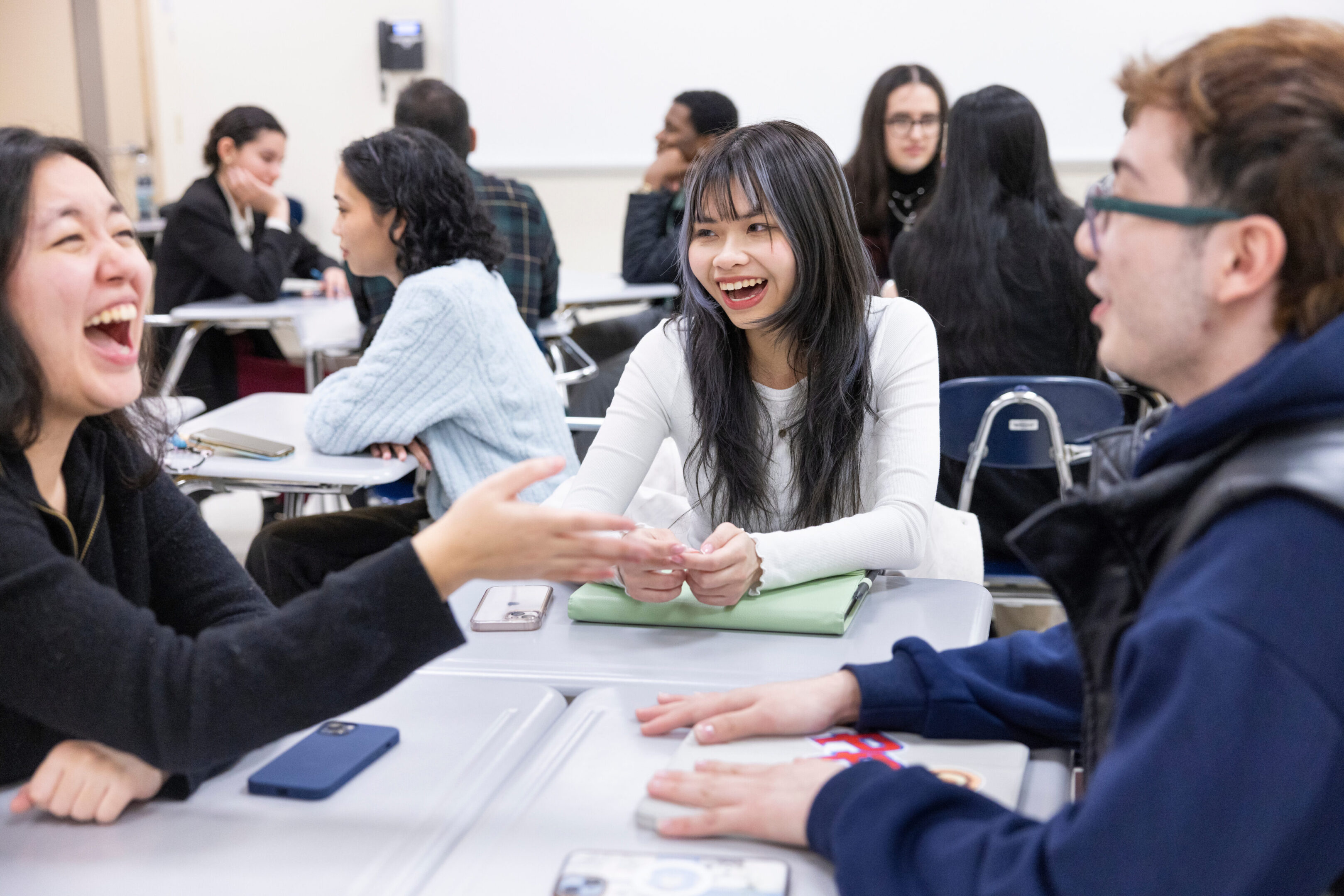 Young woman smiling and engaging with classmates in a discussion.