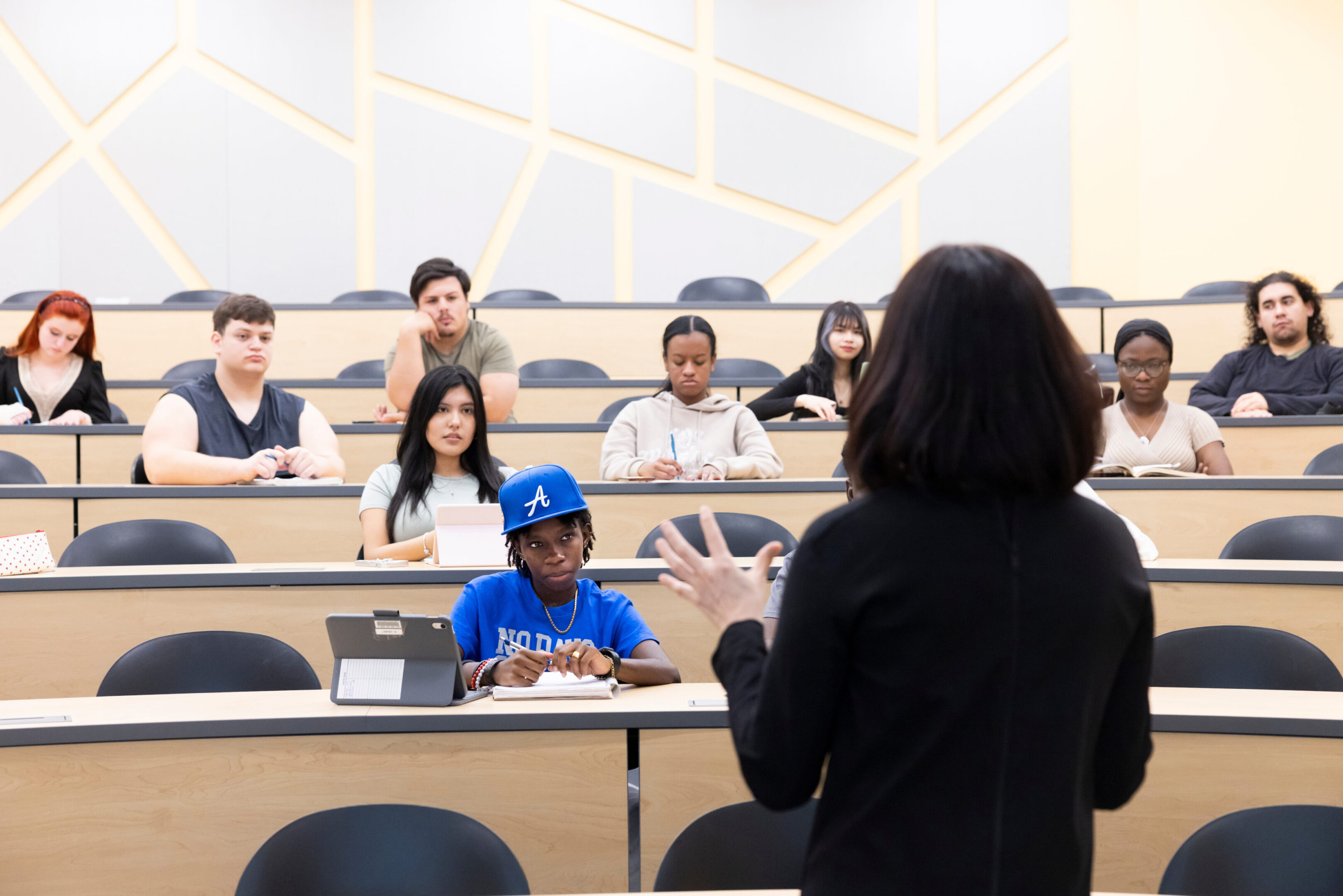 Teacher instructs diverse students in a modern classroom.