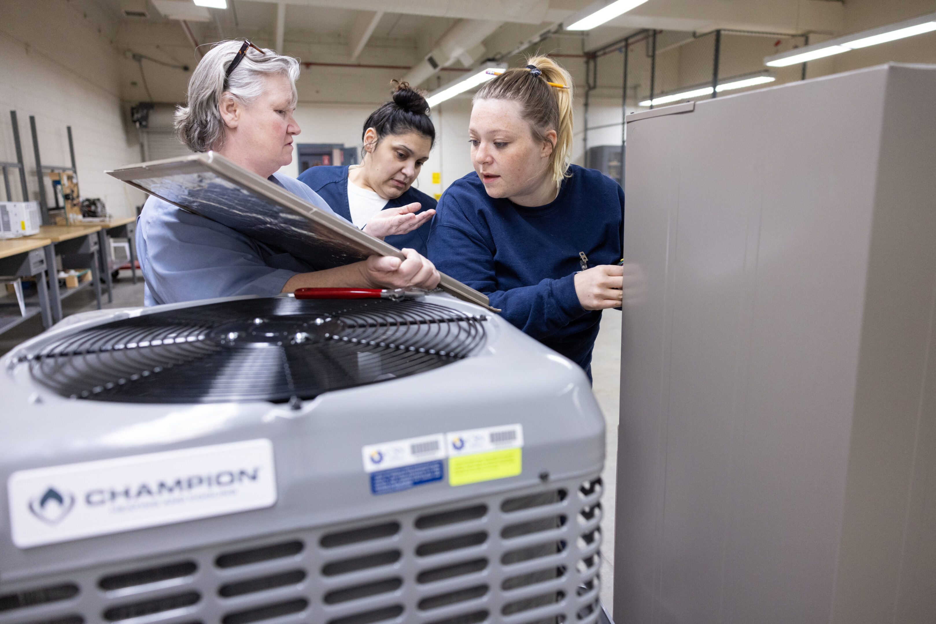 Two technicians working on industrial HVAC equipment indoors.
