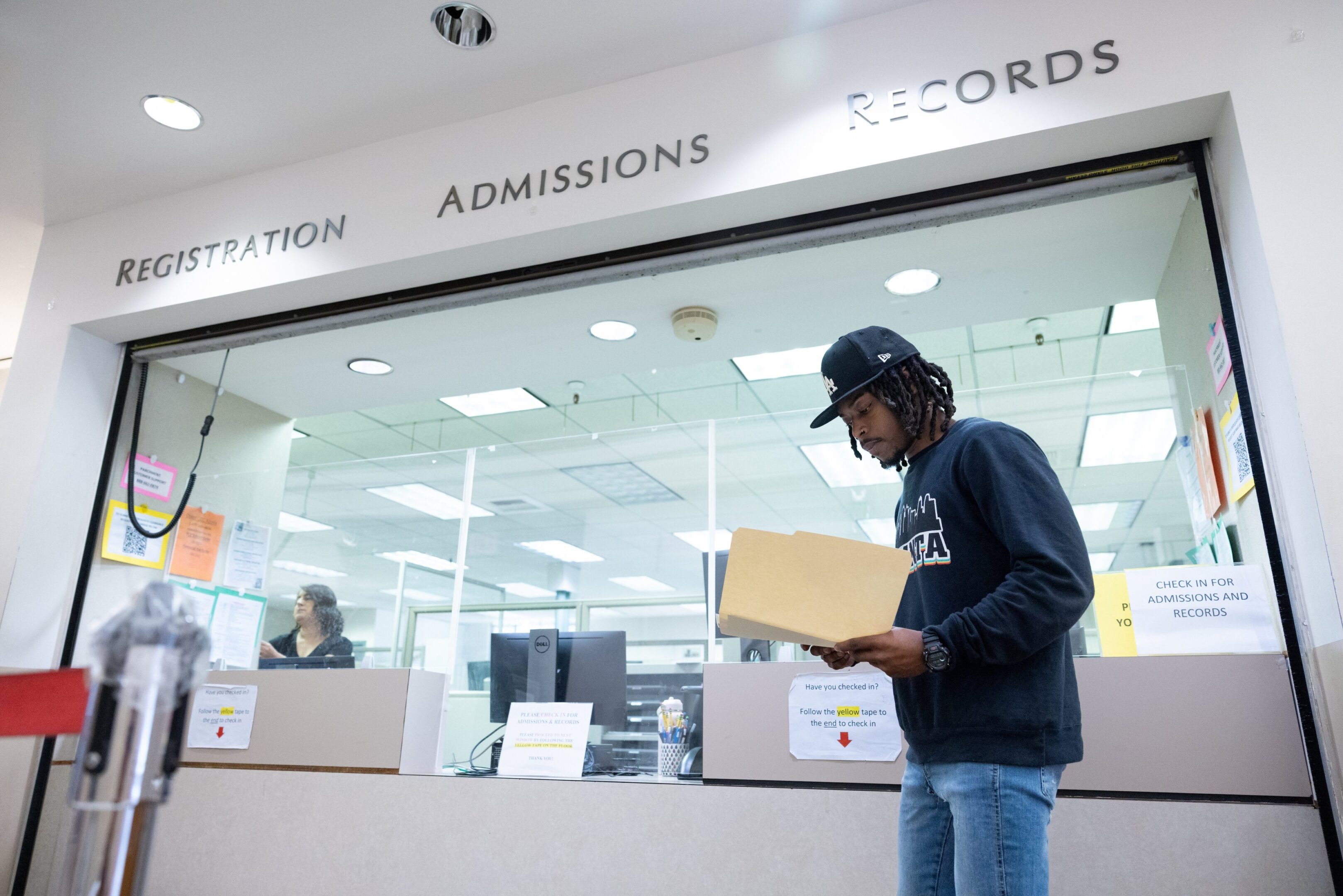 A student carrying a cardboard box inside a university admissions office.